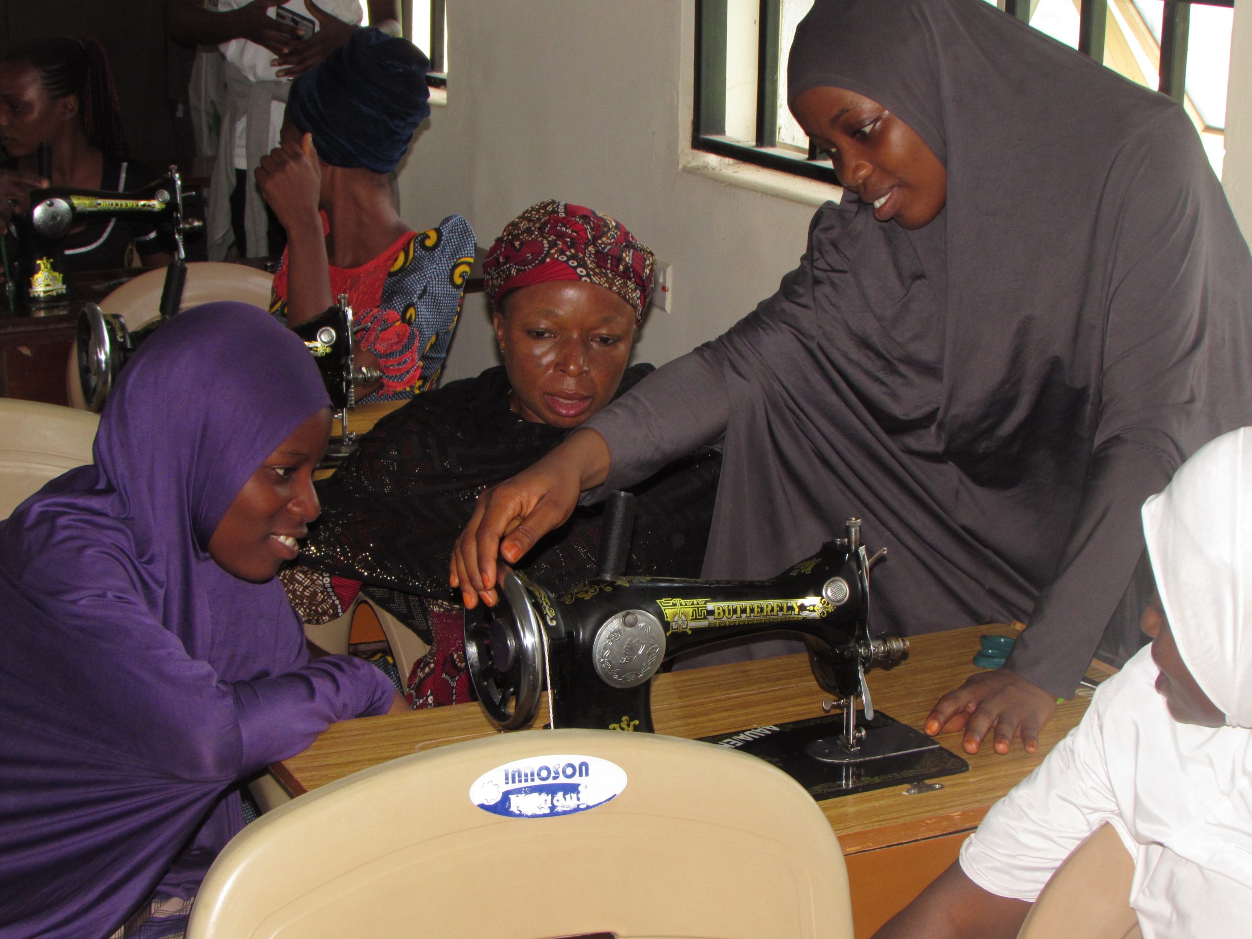 Women learning tailoring skills together